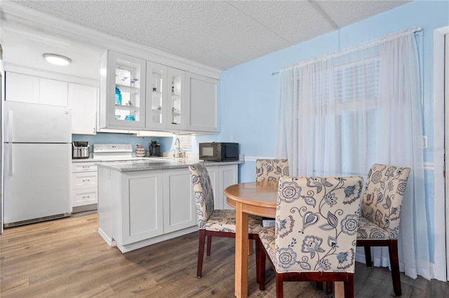 kitchen featuring white cabinetry, stove, hardwood / wood-style floors, a textured ceiling, and white fridge