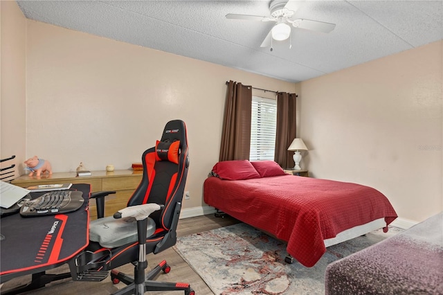 bedroom with hardwood / wood-style flooring, a textured ceiling, and ceiling fan