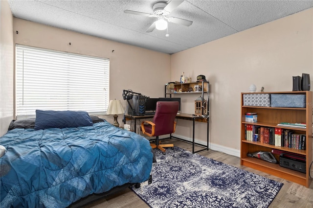 bedroom with ceiling fan, hardwood / wood-style floors, and a textured ceiling