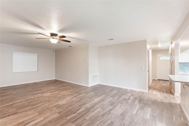 spare room featuring ceiling fan, light hardwood / wood-style floors, and a textured ceiling