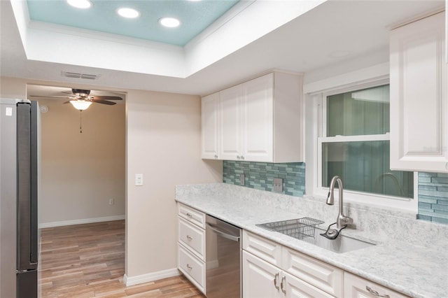 kitchen featuring a raised ceiling, sink, light hardwood / wood-style flooring, white cabinetry, and stainless steel appliances