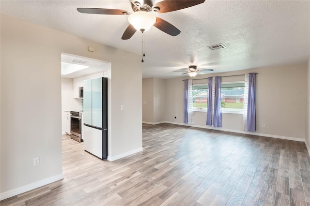 unfurnished room with ceiling fan, a textured ceiling, and light wood-type flooring