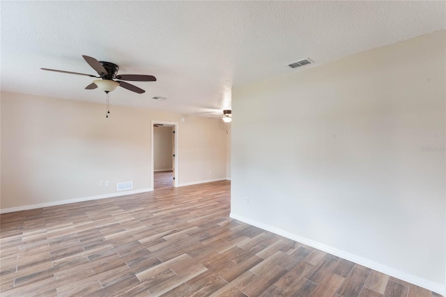 empty room with ceiling fan, light hardwood / wood-style flooring, and a textured ceiling