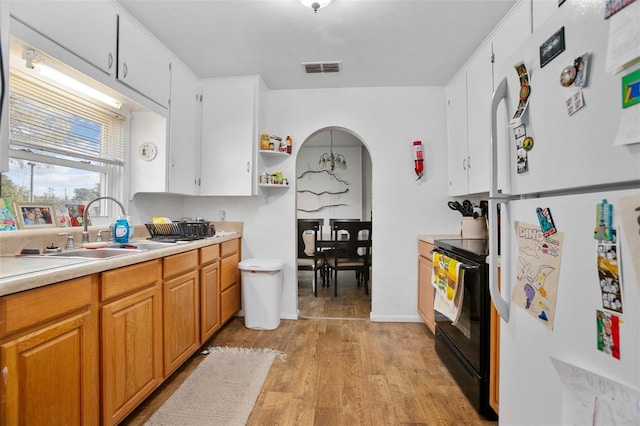 kitchen featuring white cabinets, sink, light hardwood / wood-style flooring, black range with electric cooktop, and white fridge