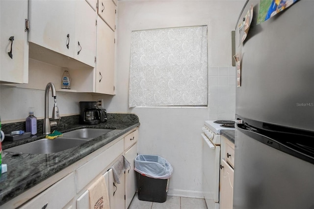 kitchen featuring white range oven, stainless steel fridge, white cabinetry, and sink