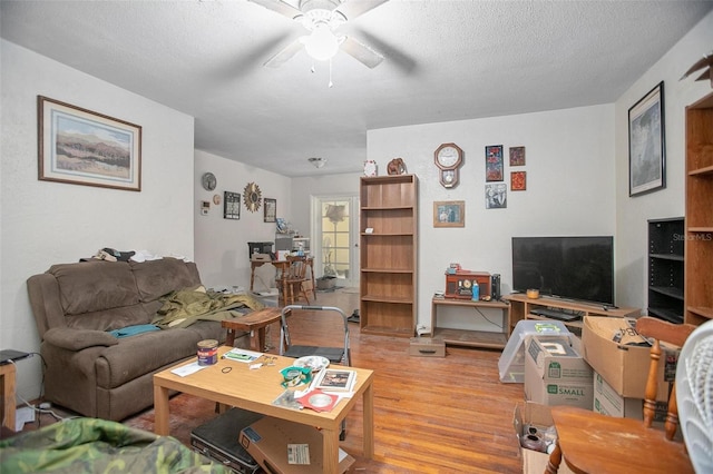 living room featuring ceiling fan, a textured ceiling, and light wood-type flooring