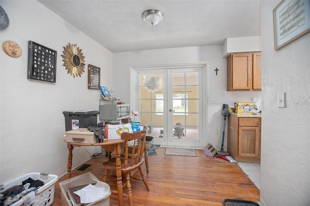 office area featuring light wood-type flooring, a textured ceiling, and french doors