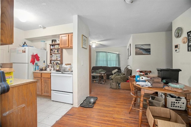 kitchen featuring a textured ceiling, white appliances, light tile patterned floors, and ceiling fan