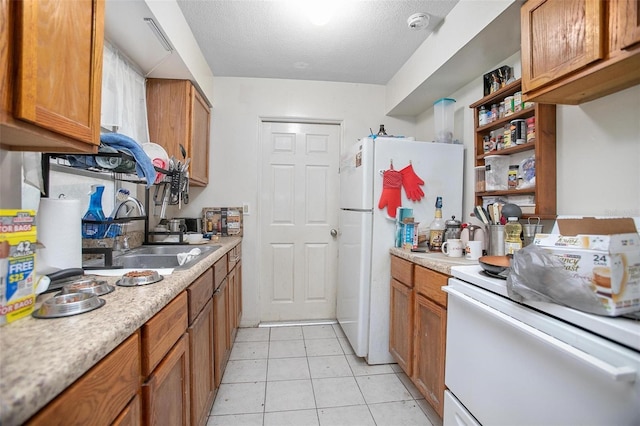 kitchen with a textured ceiling, white appliances, sink, and light tile patterned floors