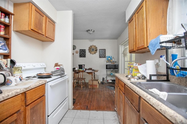 kitchen with light tile patterned flooring, white electric range, a textured ceiling, and sink