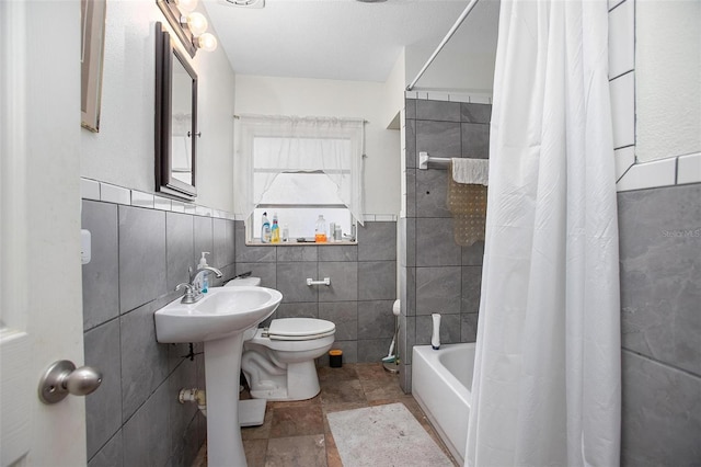 bathroom with shower / bathtub combination with curtain, toilet, and tile walls