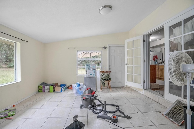 workout room featuring lofted ceiling, light tile patterned floors, and french doors