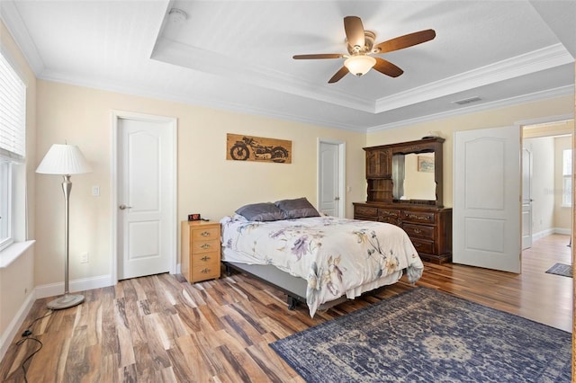 bedroom featuring hardwood / wood-style flooring, ceiling fan, a raised ceiling, and crown molding