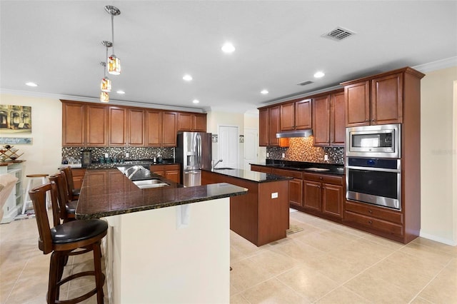 kitchen with sink, crown molding, an island with sink, a kitchen bar, and stainless steel appliances