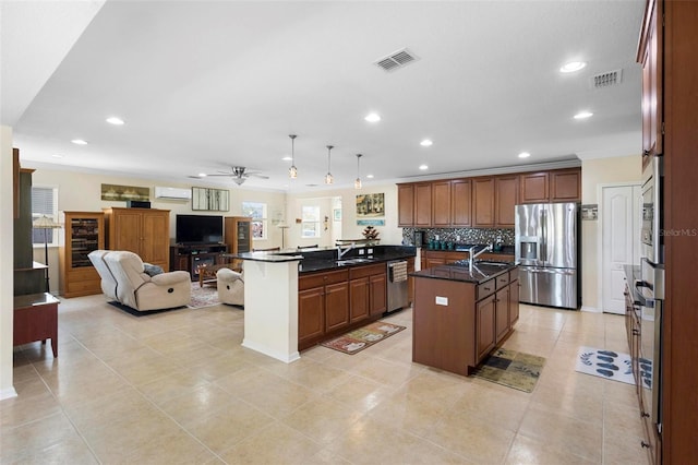 kitchen featuring backsplash, stainless steel appliances, a kitchen island with sink, ceiling fan, and pendant lighting