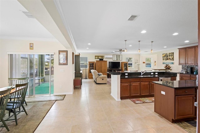 kitchen with ceiling fan, a center island, sink, crown molding, and light tile patterned floors