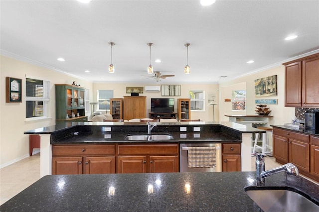 kitchen featuring decorative light fixtures, crown molding, sink, and dark stone counters