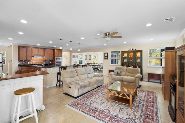 living room featuring ceiling fan, light tile patterned flooring, and crown molding