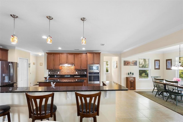 kitchen featuring a kitchen bar, appliances with stainless steel finishes, backsplash, crown molding, and hanging light fixtures