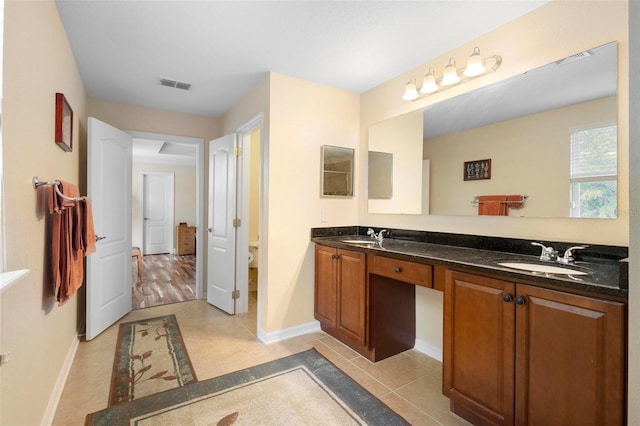 bathroom with toilet, vanity, and tile patterned floors