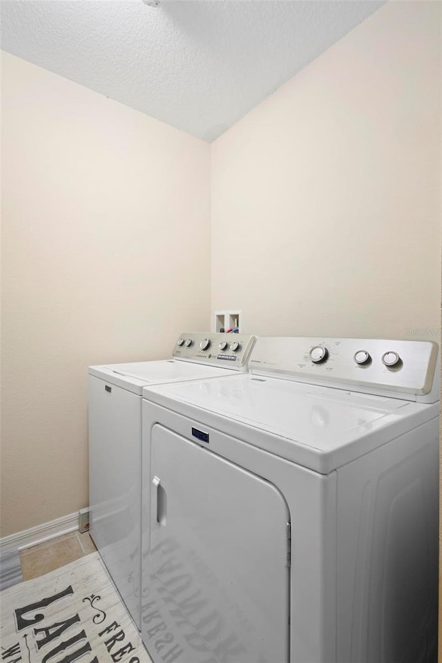 clothes washing area featuring light tile patterned floors, a textured ceiling, and independent washer and dryer