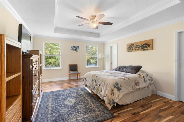 bedroom with dark wood-type flooring, ornamental molding, a raised ceiling, and a textured ceiling