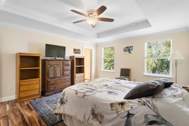 bedroom featuring hardwood / wood-style floors, ceiling fan, a raised ceiling, crown molding, and a textured ceiling