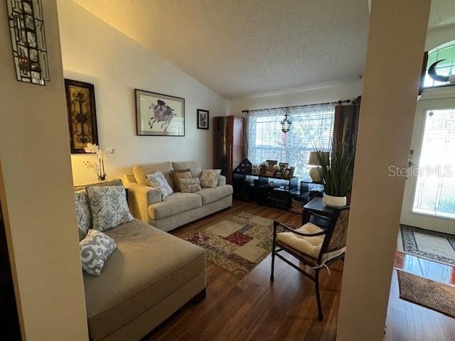 living room with hardwood / wood-style flooring, plenty of natural light, a textured ceiling, and vaulted ceiling