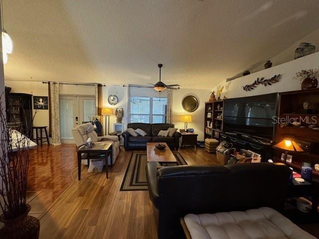 living room with french doors, vaulted ceiling, hardwood / wood-style flooring, ceiling fan, and a textured ceiling