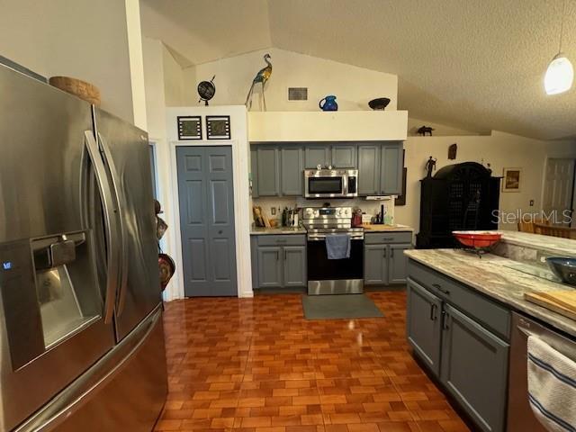 kitchen with appliances with stainless steel finishes, gray cabinetry, a textured ceiling, decorative light fixtures, and lofted ceiling