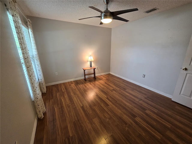 empty room with a textured ceiling, ceiling fan, and dark wood-type flooring