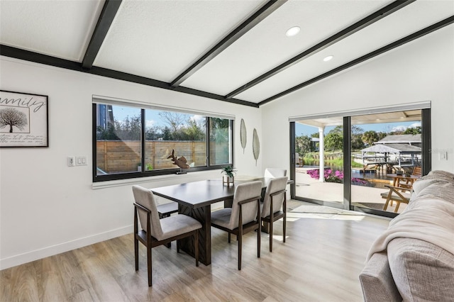 dining space with lofted ceiling with beams, light wood-type flooring, and plenty of natural light