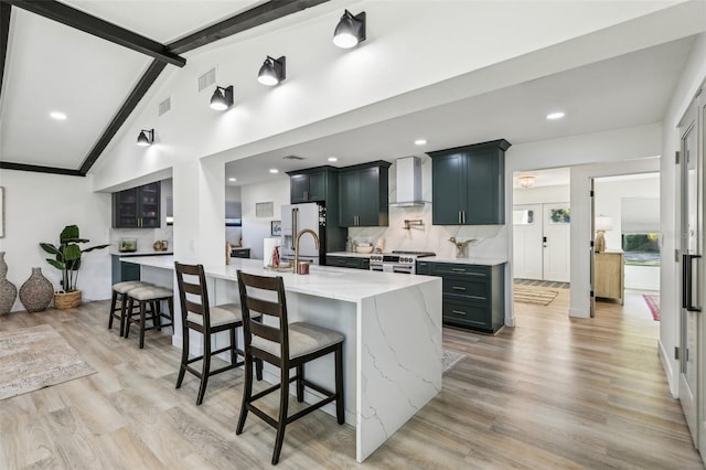 kitchen featuring vaulted ceiling with beams, a breakfast bar area, a large island, and wall chimney range hood