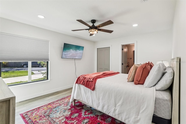 bedroom featuring ensuite bath, ceiling fan, a closet, and light wood-type flooring