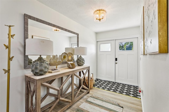 foyer with a textured ceiling, light hardwood / wood-style flooring, and a notable chandelier