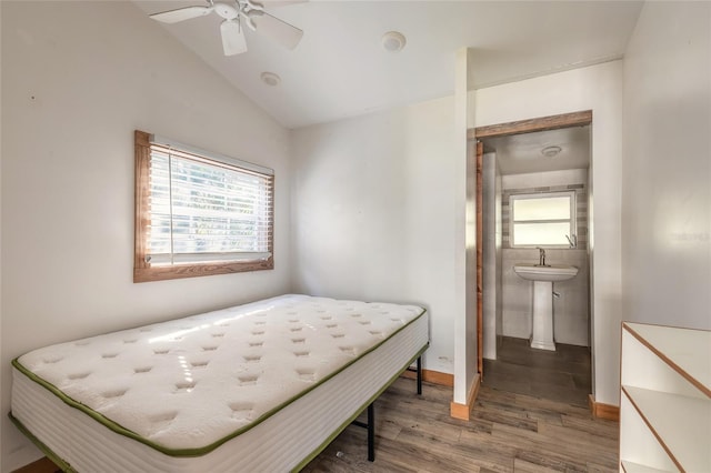 bedroom featuring ensuite bathroom, ceiling fan, sink, hardwood / wood-style flooring, and lofted ceiling