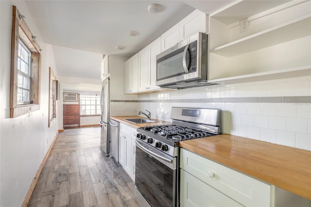 kitchen with butcher block counters, white cabinetry, sink, and appliances with stainless steel finishes