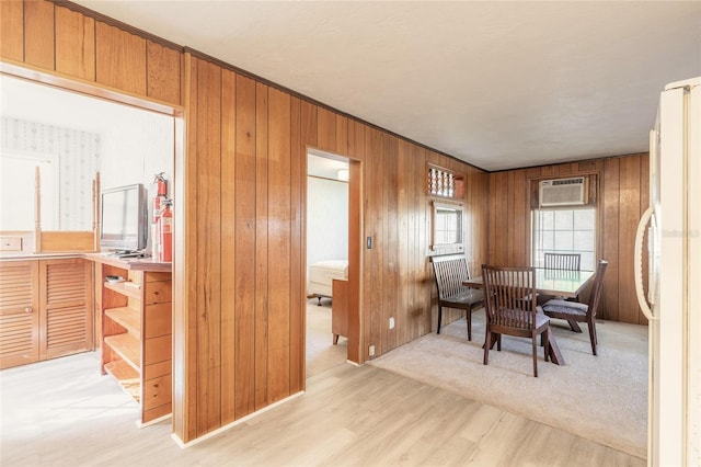 dining room featuring light wood-type flooring, an AC wall unit, and wooden walls