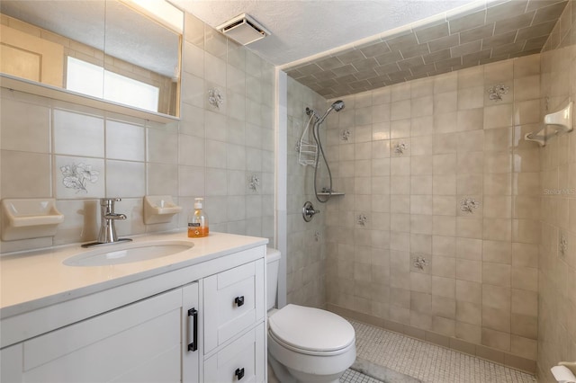 bathroom with vanity, backsplash, toilet, tiled shower, and tile walls