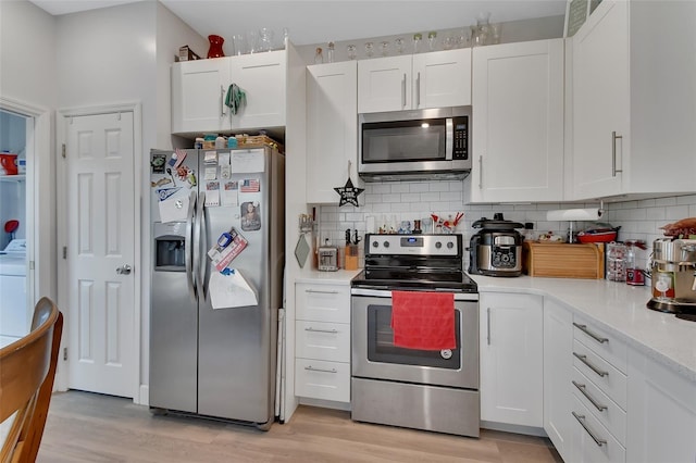 kitchen with backsplash, white cabinetry, light hardwood / wood-style flooring, and stainless steel appliances