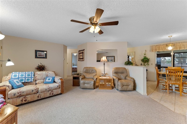 living room with ceiling fan, carpet floors, and a textured ceiling