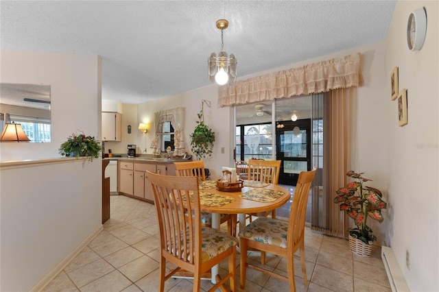 tiled dining room featuring baseboard heating, sink, and a textured ceiling