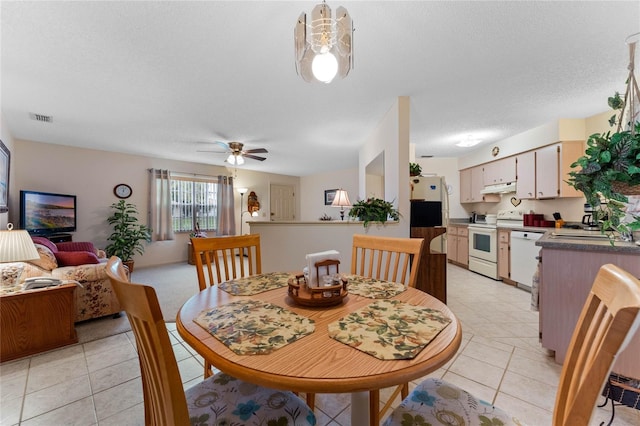 dining area featuring light tile patterned flooring, ceiling fan, sink, and a textured ceiling