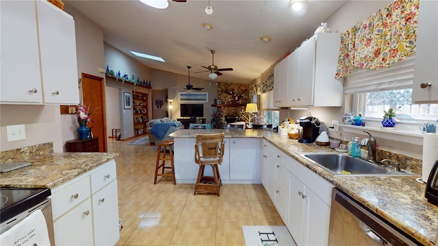 kitchen featuring a kitchen breakfast bar, white cabinetry, sink, and vaulted ceiling with skylight