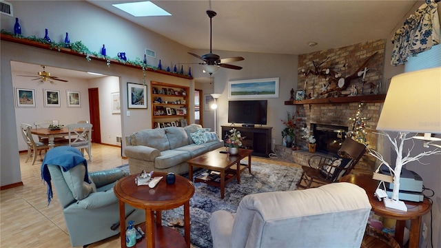 living room featuring a fireplace, tile patterned flooring, lofted ceiling with skylight, and ceiling fan