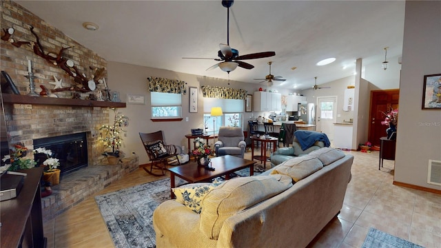 living room with ceiling fan, light tile patterned floors, a fireplace, and vaulted ceiling