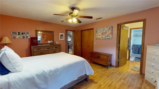 bedroom featuring a closet, ensuite bathroom, light hardwood / wood-style flooring, and ceiling fan