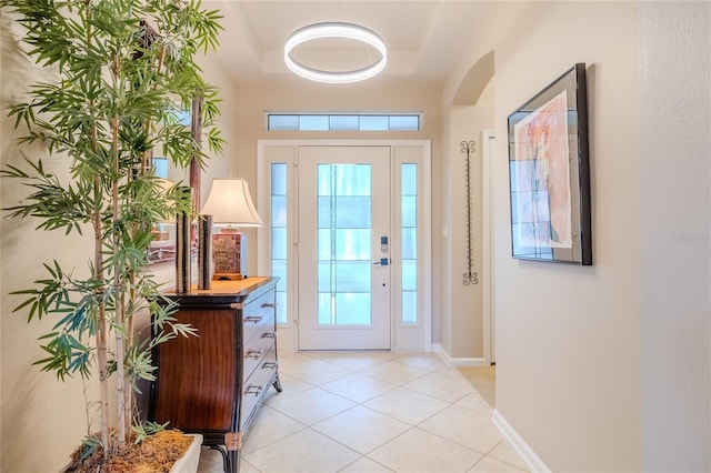 tiled entryway featuring plenty of natural light and a tray ceiling