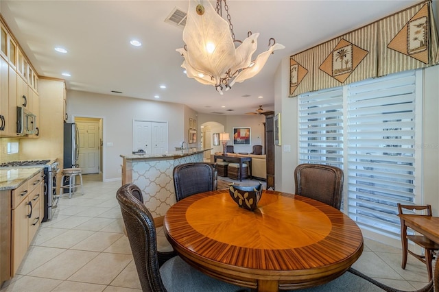 dining room with light tile patterned floors and ceiling fan with notable chandelier