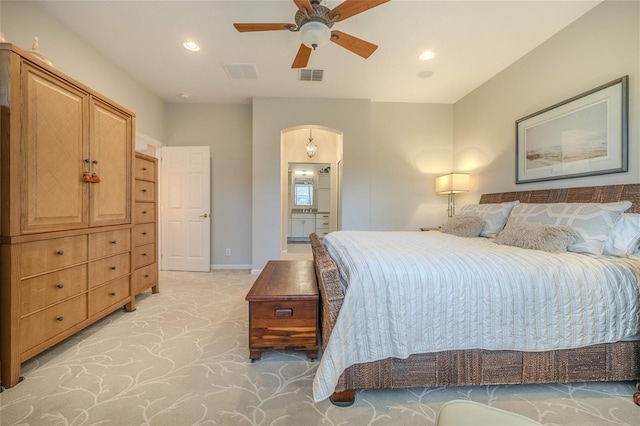 bedroom with ceiling fan, light carpet, and ensuite bath